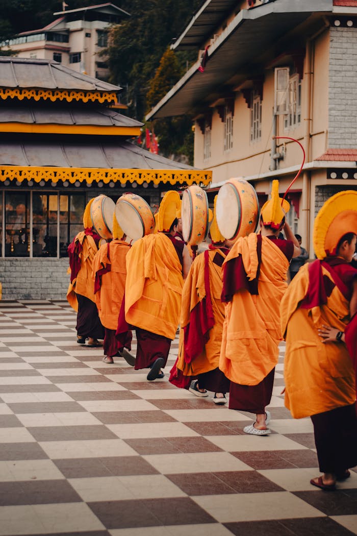 Buddhist monks in traditional costumes walking at a temple in Gangtok, Sikkim, India.